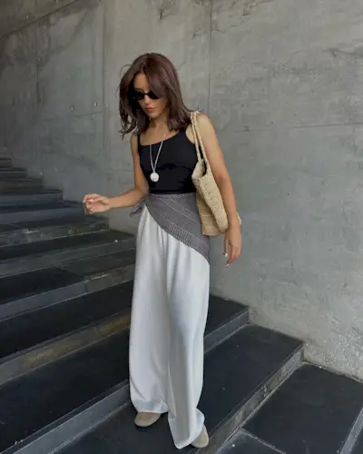 Woman in white flowy pants and black tank top.