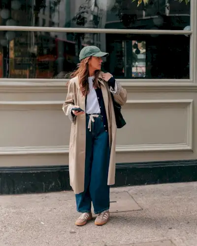 Fashion person Kim Turkington wears the drawstring jean trend. She pairs in with beige trainers, a white t-shirt black cardi and beige trench in a recent image from her Instagram.
