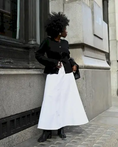 Danielle in a white A-line skirt and black cardigan