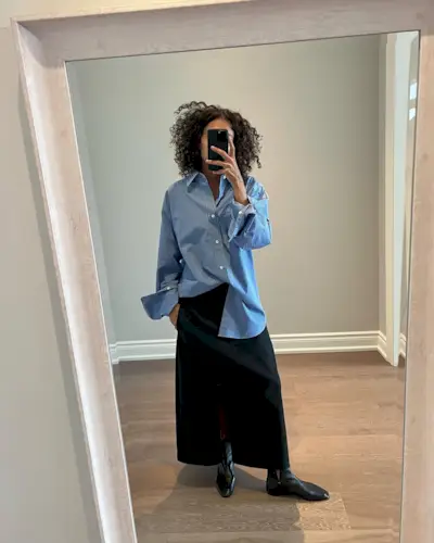 Neelam in a blue striped top and black skirt and boots