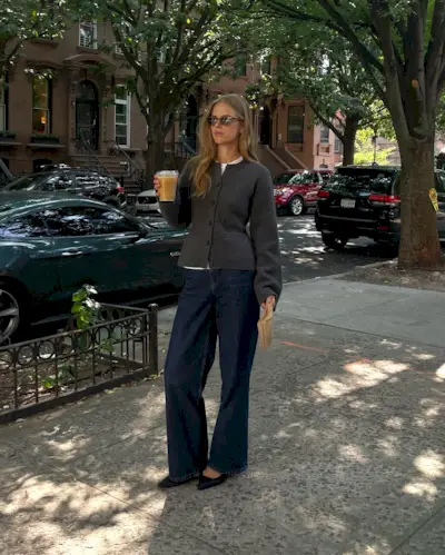 Woman wears waisted cardigan, blue jeans and black bag