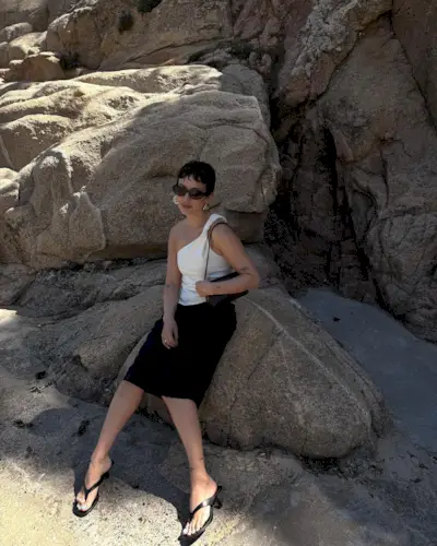 woman on the beach in white top and black skirt