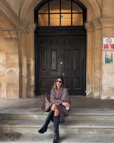Woman wearing sweaterdress and tall black boots.