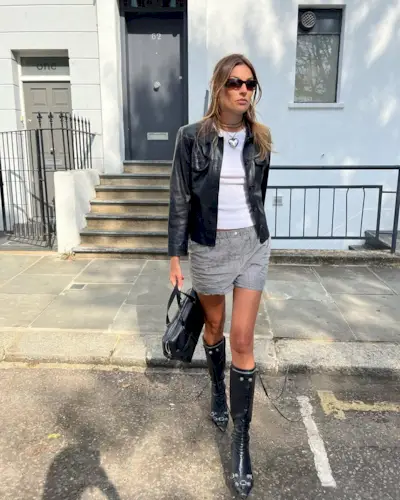 Woman wearing boxer shorts, leather jacket, and tall black boots.