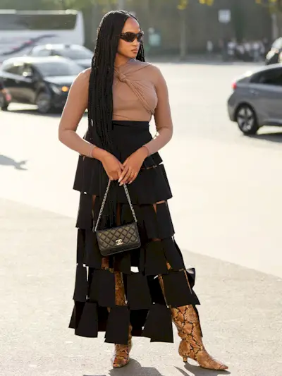 a photo of a woman wearing a cute black bra under a sheer brown shirt with a skirt and snakeskin boots