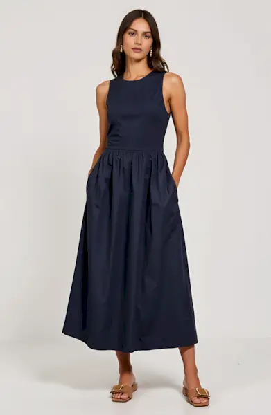 Influencer Anna wears a striped polo sweater and a gray skirt with a brown belt, black loafers, and a light-colored leather bag.