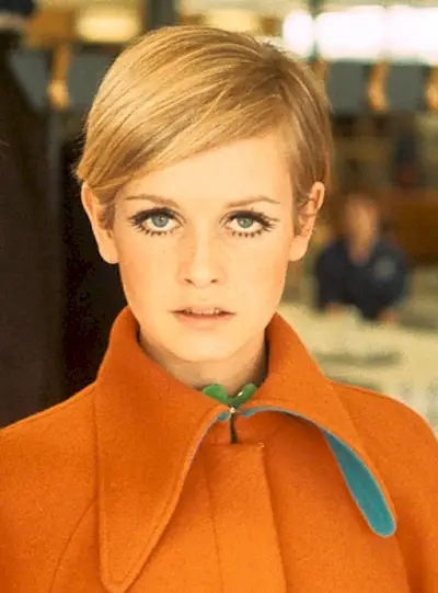 Twiggy wearing an orange coat.