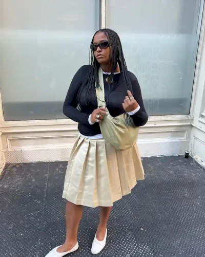 @champagnemani wearing a pleated skirt with jumper and flats