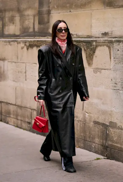 a street-style photo of a woman carrying a Hermés bag in a story about how to buy an hermés bag
