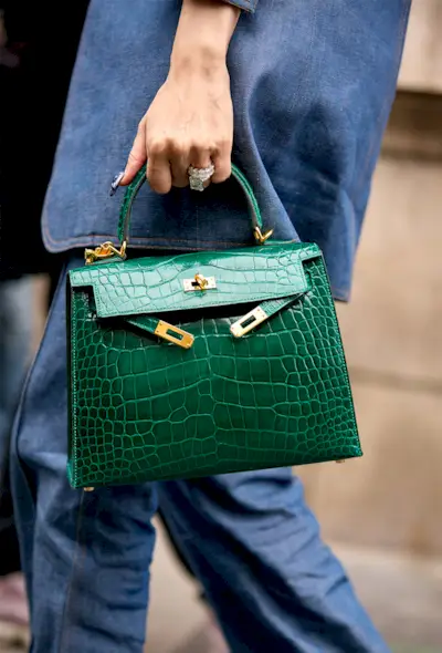 a street style photo of a woman carrying an Hermés bag in a story about how to buy an hermés bag