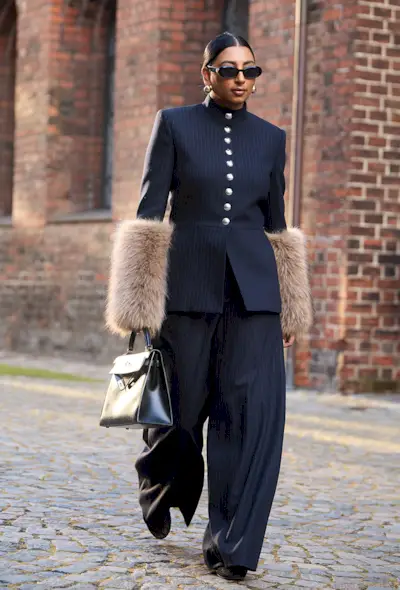 a street style photo of a woman carrying an Hermés bag in a story about how to buy an hermés bag