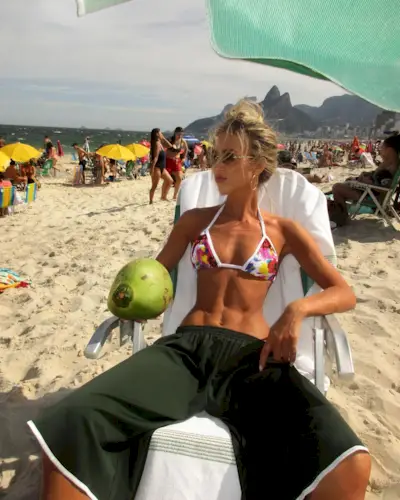 A woman wearing a bikini top and green athletic shorts.