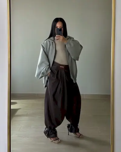 @oumaymaboumeshouli wearing a gray jacket and brown Loewe leather genie pants.