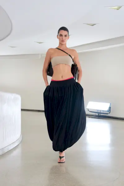 Kendall Jenner is wearing a bandeau top and black genie pants on the runway at Alaïa