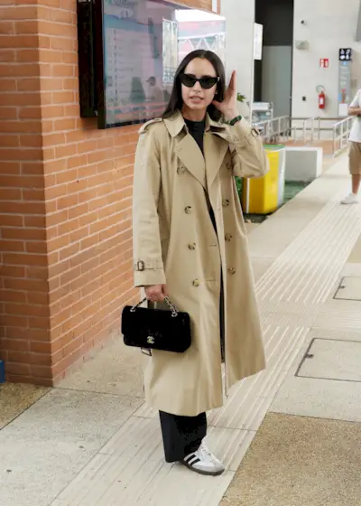 Sofia wears a trench coat, chanel bag, black trousers, and adidas samba sneakers.