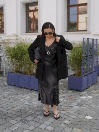 @indiraci wears a black polka dot dress with a blazer and flip-flops
