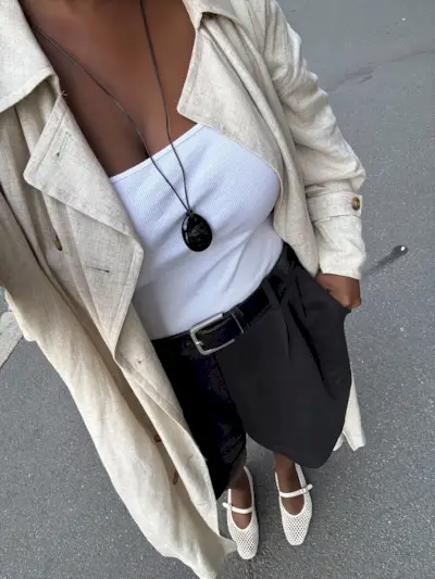Woman in white tank top, black shorts with black pendant necklace.
