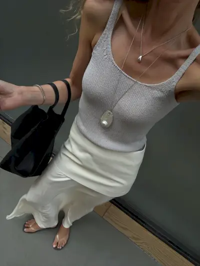 Woman in tank top, long skirt, and long pendant necklace