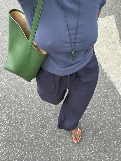 Woman in navy top, pants, and green pendant