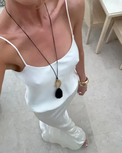 Woman in long pendant necklace and white dress