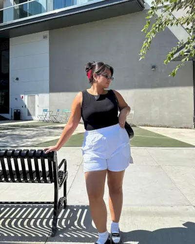A woman wears a black tan, white boxer shorts, white socks and loafers.