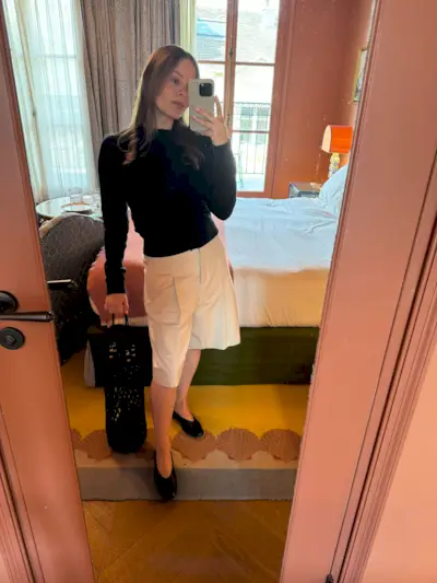 Nikki wears a black sweater, long bermuda shorts, and black ballet flats.