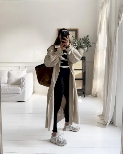 Jessica wears a trench coat, striped jumper, leggings and running trainers