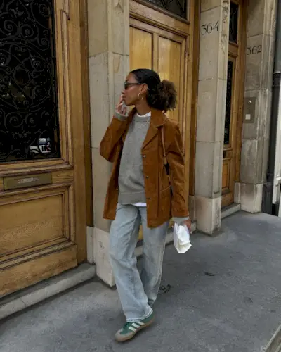 fashion influencer Amaka Hamelijnck wearing a brown suede jacket, relaxed jeans, and green suede Adidas Sambas