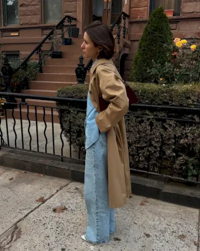 Woman wears beige trench coat and blue jeans