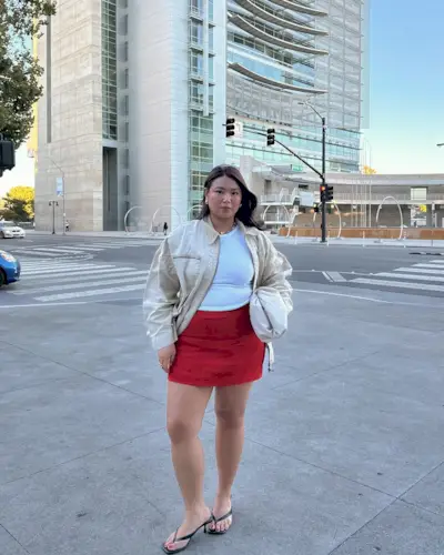 @marina_torres wears a red miniskirt with a beige jacket and white clutch bag