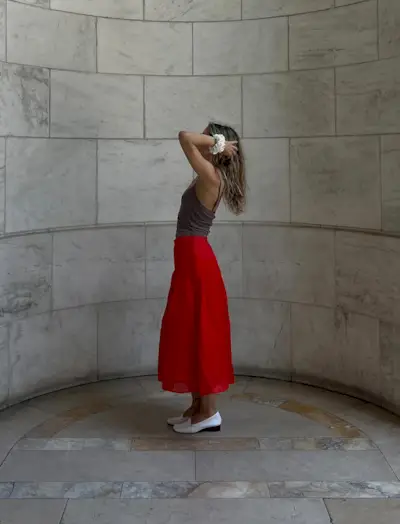 @elizahuber wears a red satin skirt with white shoes and a grey vest top