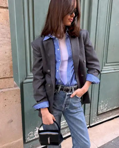 woman wearing a gray blazer, blue stripe shirt, and jeans