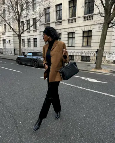 Influencer @georgia_3.0 wears a brown suede blazer with a black turtleneck, black trousers and black pointed-toe boots.