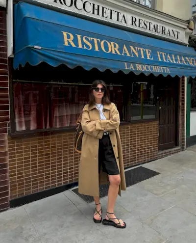 Woman wears trench coat, linen shorts, sandals
