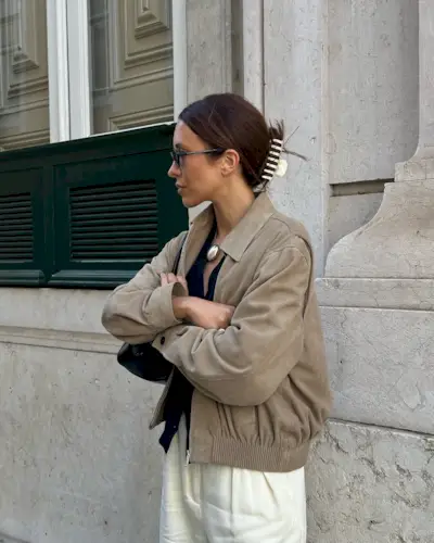 Woman wears brown suede jacket, black T-shirt, white jeans and suede shoes