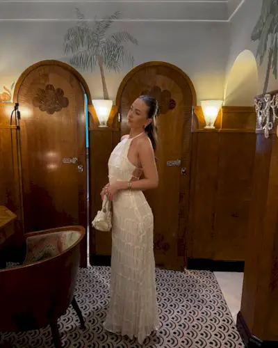 An image of @yesitsnicolee wearing a white halterneck dress while in London.