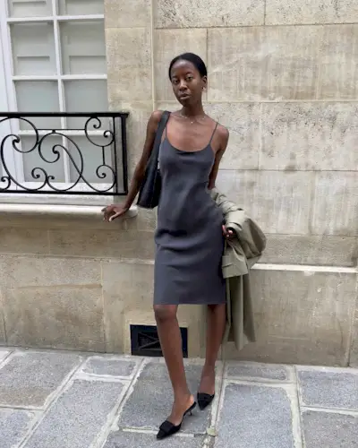 Sylvie Mus wearing a slip skirt, kitten heels, a shoulder bag, and a trench coat.