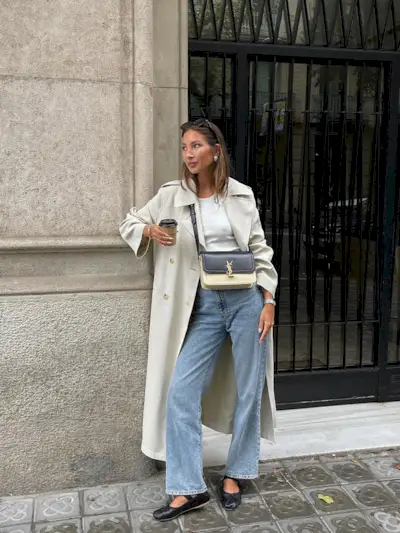 a photo of a woman wearing sunglasses, a trench coat, a tank top, jeans, ballet flats, and a YSL shoulder bag