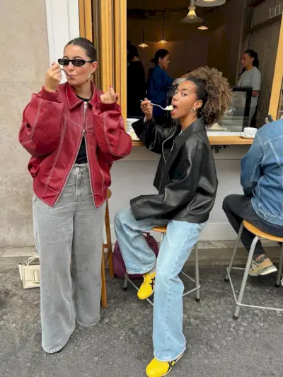 @amaka.hamelijnck and @bentheliem outside a cafe weating on-trend leather jackets and jeans.