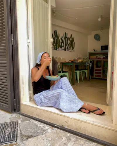 woman sitting eating pasta in tank top and striped pants