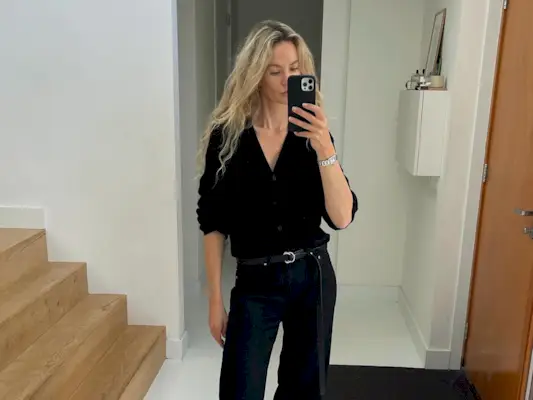 @anoukyve wearing a chic and easy all-black winter outfit with a cardigan, jeans, and boots.