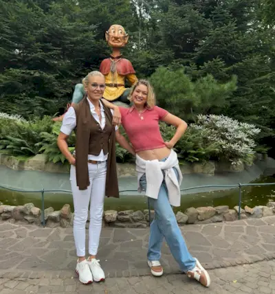 Yolanda and Gigi Hadid pose in front of a statue wearing sneakers.