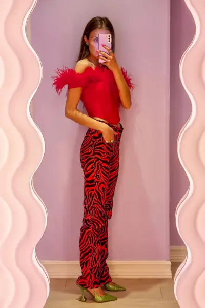 a woman's corset top outfit with a red feather bustier styled with red zebra print jeans and green sparkly pumps