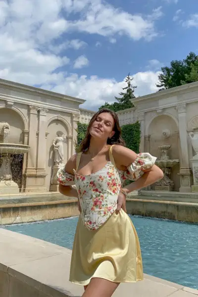a woman's corset top outfit with a white and floral puff sleeve bustier styled with a yellow slip skirt