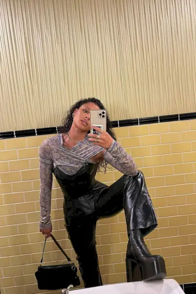 a woman's corset top outfit with a leather bustier layered over a floral print mesh top with leather pants and platform boots