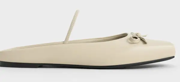 Influencer Anouk Yve styles black flat mules with Toteme black trousers, and white Arket white jumper and a gray Carolina Herrera bag.