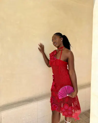 Nana Agyemang wearing a red one-shoulder crochet dress with flower embellishments.