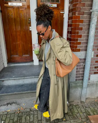 @ amaka.hamelijnck wearing a jumper, jeans, trench and yellow trainers