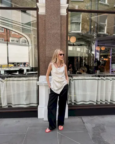 @chloekathbutler wears red flip-flops with a cream silk top and black trousers