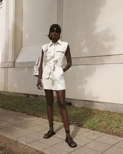 A woman wearing a utilitarian-inspired short jumpsuit with lace-up black sandals.